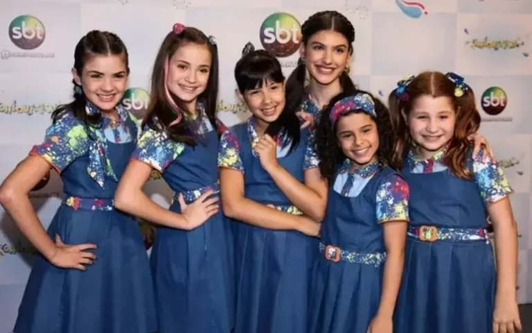 Elenco infantil de 'Chiquititas' em uniformes azuis, posando sorridentes diante do logo do SBT.