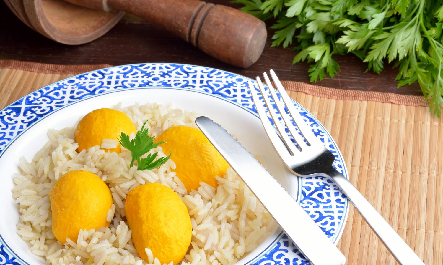 Prato de arroz com pequi, servido em um prato decorado, acompanhado por um ramo de salsa. O pequi, de cor amarela vibrante, contrasta com o arroz branco, destacando a simplicidade e os sabores da culinária do Cerrado brasileiro.